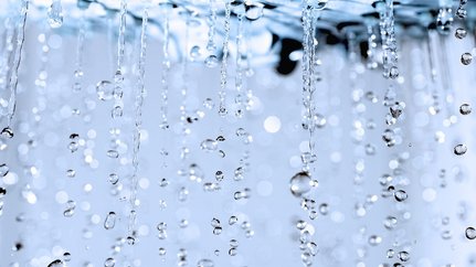 Faszinierende Tropfen, die im Licht funkeln Wassertropfen fallen in einer sanften Bewegung, während sie im Licht funkeln und eine ruhige Atmosphäre schaffen.