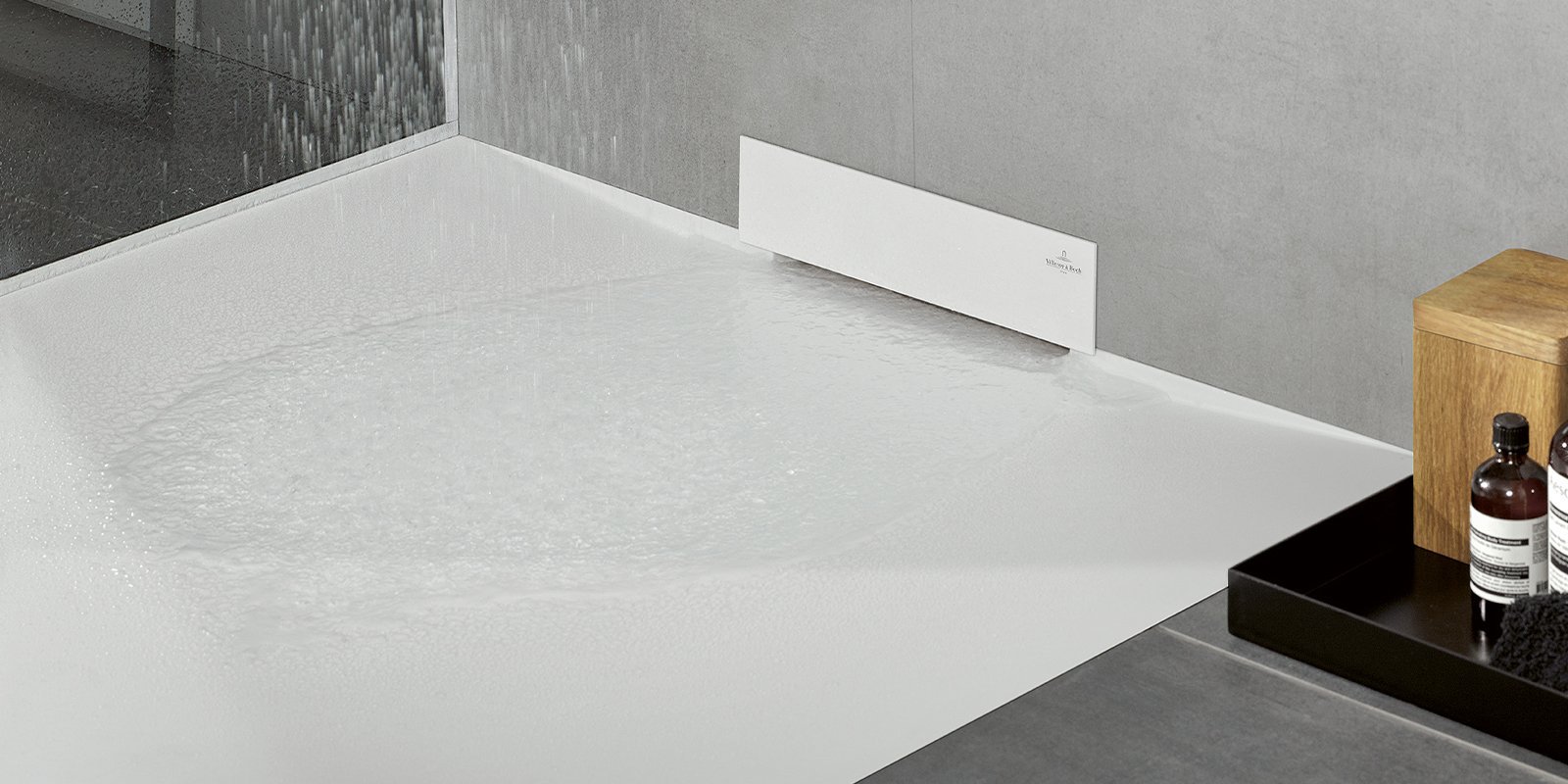 Ein moderner Duschbereich mit einem weißen Boden, auf dem Wasser steht, und einer eleganten Wandverkleidung aus Beton.