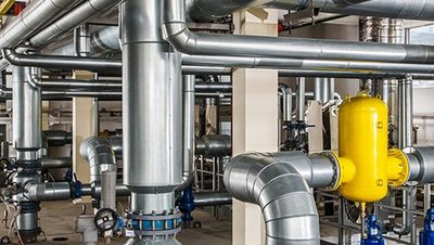 Ein Raum mit einer Edelstahl Rohranlage, Pumpen und Kompressoren.