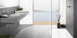 Ein modernes Badezimmer mit einem eleganten Waschbecken aus Beton und Blick auf einen ruhigen See durch große Fenster.